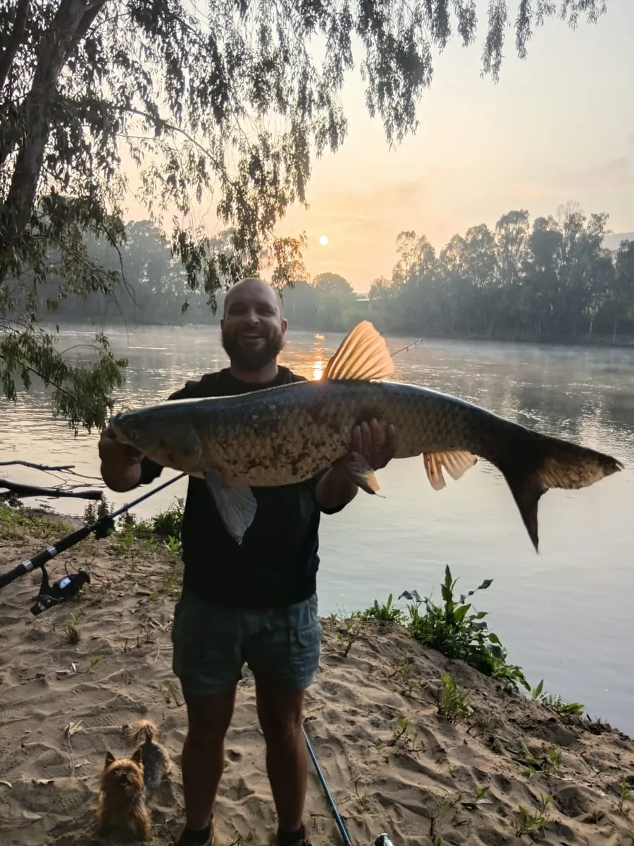 Angler holding a large fish at sunrise on the river