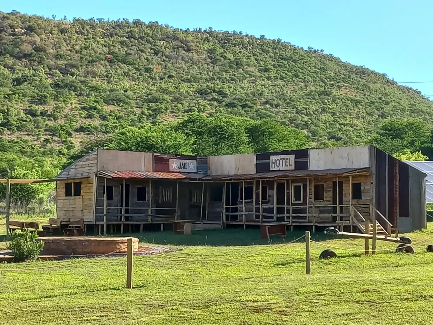 Western-style saloon buildings at the foot of a green hill