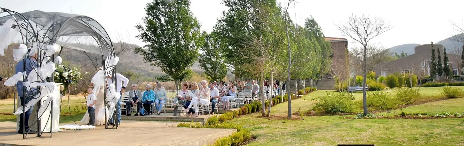Guests seated for a garden ceremony with the hills behind