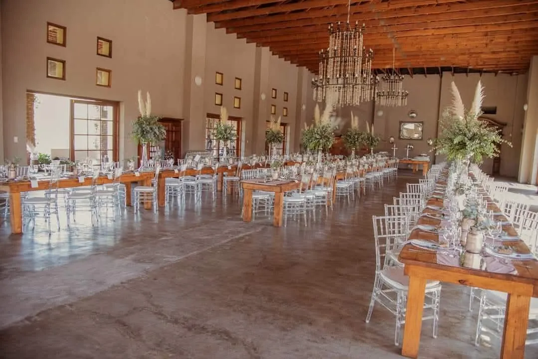 Reception hall set with long wooden tables and chandeliers