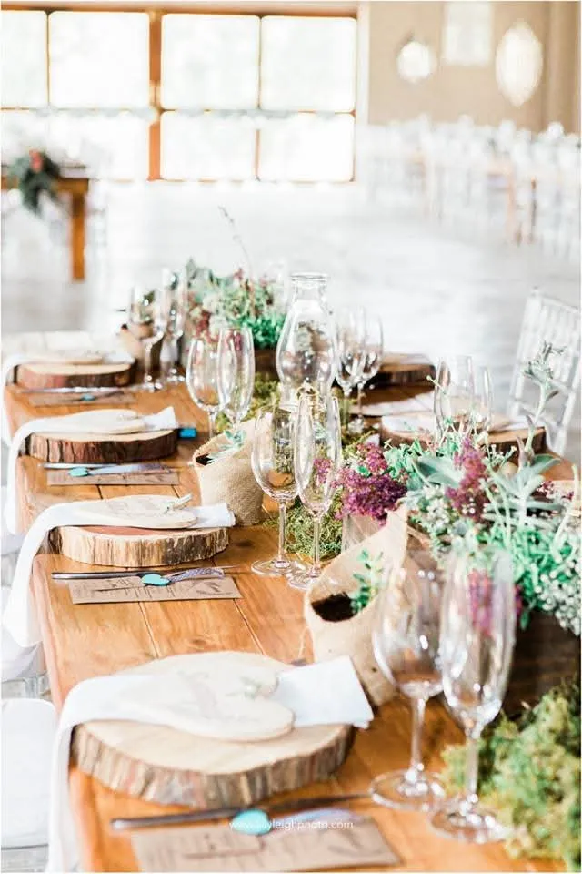 Long table with wooden chargers, glassware and flowers